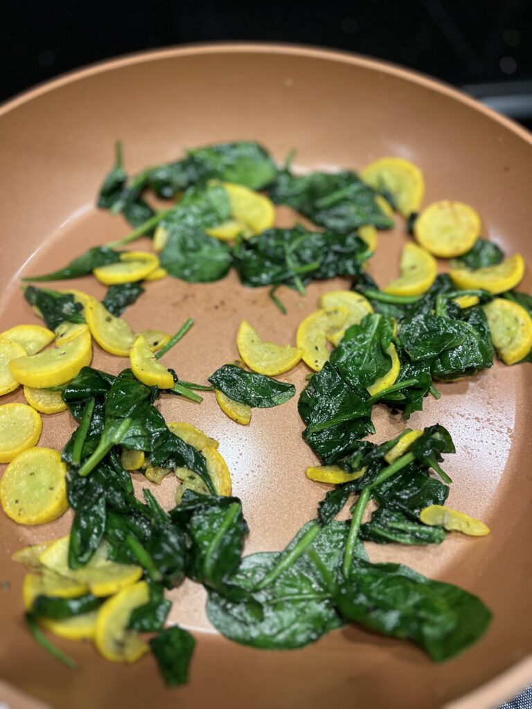 wilted spinach and yellow squash in pan